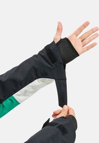 Schwarzer, mehrlagiger Jackenärmel mit grünen und weißen Akzenten, ausgestattet mit einem Daumenloch und einem Klettverschluss für sicheren Halt.