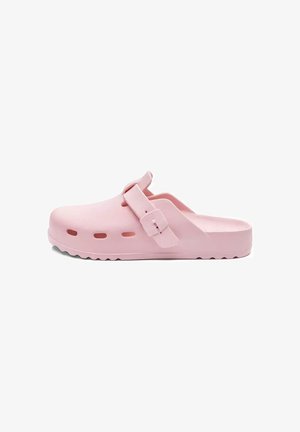 Jasnoróżowe chodaki wsuwane z otworami wentylacyjnymi, regulowanym paskiem i fakturowaną podeszwą, prezentowane na białym tle.