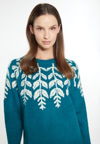 Pulover tricotat de culoare teal, cu un design în frunze albe, având un guler rotund și mâneci lungi, realizat dintr-un material moale și texturat.