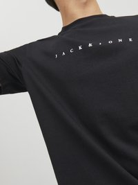 Schwarzes T-Shirt mit kurzen Ärmeln aus Baumwolle, mit dem weißen Text "JACK & JONES" auf dem oberen Rücken, glatte Textur und lockere Passform.