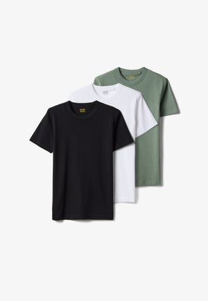 Tres camisetas lisas con cuello redondo en negro, blanco y verde apagado, superpuestas y mostradas sobre un fondo blanco.