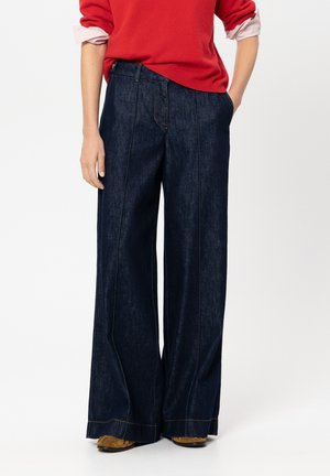Wide-leg dark denim trousers with a high waist, featuring contrast stitching and side pockets. Paired with a red sweater.