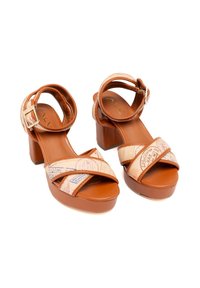 Sandali piattaforma color talpa con tacco a blocco, dotati di cinturini incrociati in un motivo talpa stampato che ricorda i timbri di viaggio. Cinturino alla caviglia regolabile.