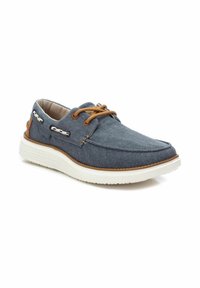 Scarpe casual da uomo in denim blu scuro con dettagli marroni, suola in gomma bianca e lacci. Presentano una texture liscia e una punta arrotondata.