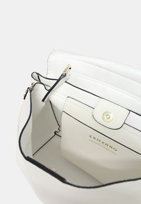 Borsa a mano in pelle bianca con una texture liscia, rifiniture nere, un pulsante dorato di chiusura e scomparti interni per l'organizzazione.