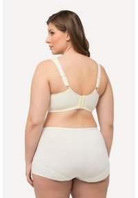 Sujeción color crema con tirantes ajustables y cierre de gancho, combinado con braguitas hipster a juego. Textura suave, diseño minimalista y sin patrones visibles.