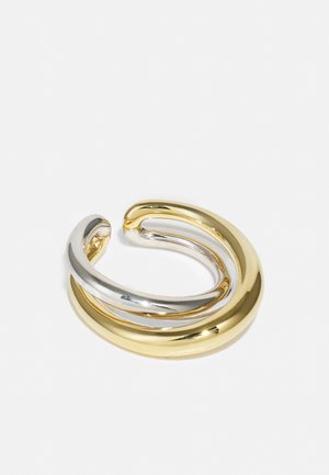 Gold and silver metallic ring, featuring two wavy bands intertwined. Smooth, shiny surface with a modern, minimalist design.