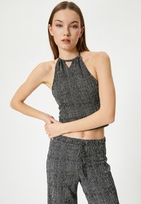 Top halter de rayas verticales en blanco y negro combinado con pantalones a juego, que cuentan con una cintura elástica y una tela texturizada.