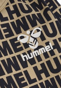Beżowy materiał z powtarzającym się czarnym wzorem graficznym oraz białym logo z stylizowanym wzorem owada, podkreślającym nazwę marki "hummel."