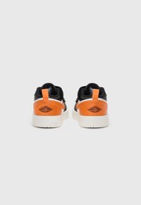 Sneakers neri con accenti arancioni, realizzati in materiale di pelle liscia e con una suola in gomma bianca. Dettaglio del logo ben visibile sul tallone.