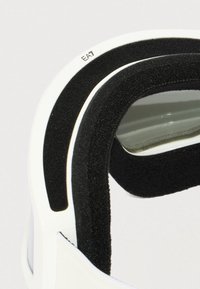 Κοντινό πλάνο λευκού headset VR με μαύρο αφρώδες μαξιλάρι και διάφανο φακό, όπου είναι μερικώς ορατό το λογότυπο "EA7".