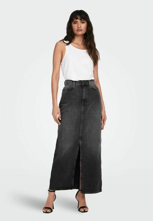 Black denim maxi skirt with a front slit, high waist, and belt loops, paired with a white tank top and black heeled sandals.