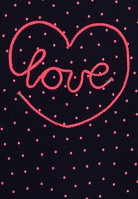 Námořnická tkanina s malými růžovými puntíky, na které je vyšitý růžový text "láska" ve tvaru srdce, s hladkým povrchem a lesklými akcenty.