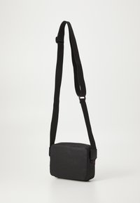 Svart crossover-väska med rektangulär form, textilstruktur, justerbar rem och dragkedjestängning. Inga synliga mönster eller hårdvaruaccent.
