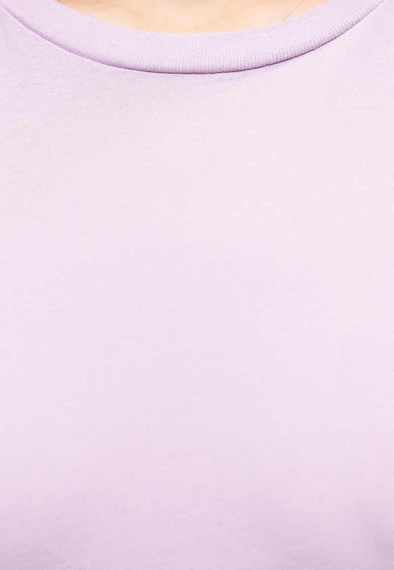 Närbild av ljuslila tröjtyg med rund hals, på övre delen av bröstet och halslinningen.