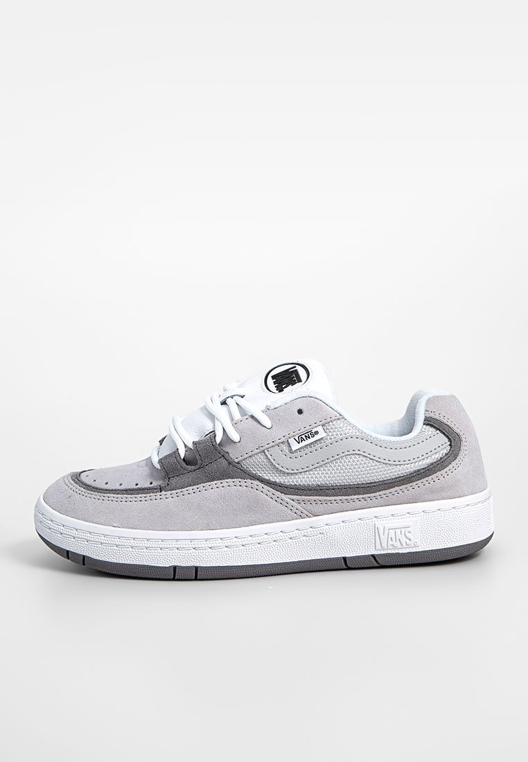 Sneaker grigia in suede con lacci bianchi, inserti in rete e suola in gomma testurizzata. Presenta una toppa con logo sul lato e cuciture distintive.