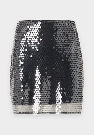 Μαύρη μίνι φούστα καλυμμένη με γυαλιστερές ασημένιες παγιέτες που αντανακλούν το φως, με μια λεία, εφαρμοστή σιλουέτα.