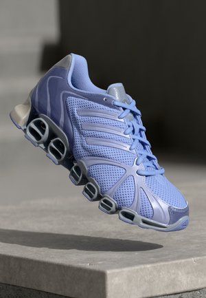 Chaussure de sport violet clair avec dessus en mesh ventilé et semelle segmentée unique flottant au-dessus d’une surface en béton.