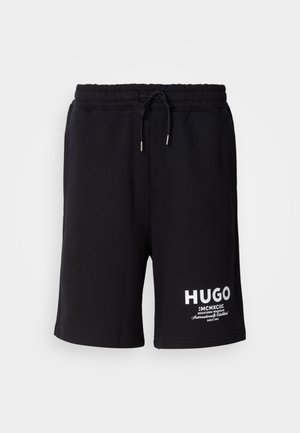 Black cotton shorts with an elastic waistband and drawstring. White "HUGO" logo on the left leg. Simple design, knee-length cut.