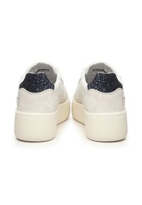Witte sneakers met een gestructureerde platformzool, voorzien van een suede hiel en een donkere glinsteraccent aan de achterkant. Gladde leren bovenkant.