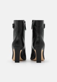 Svarta läderankelboots med rundad tå, klackblock och sidoförslutning med dragkedja. Har ett dekorativt spänne på utsidan.