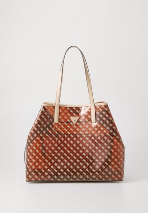 Brun og beige Guess tote-taske med logo over det hele, beige håndtag og trekantet logoplaket foran.