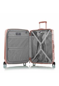 Hartschalenkoffer in Roségold. Innenausstattung aus grauem Stoff mit Netzfächern und Kreuzgurten zur Sicherung der Gegenstände. Ausziehbarer Griff und Rollen.