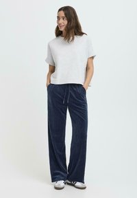 Grå kortærmet t-shirt kombineret med marineblå corduroy bukser med snoretræk i taljen, sidelommer og blød tekstur, afsluttet med hvide sneakers.