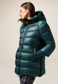 Teal pufferjack met capuchon, voorzien van een ritssluiting, zijzakken en een gestikte uitstraling. Gladde textuur en glanzende afwerking.
