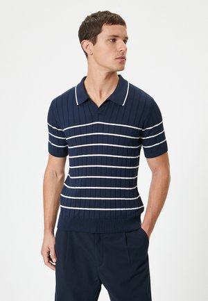 Polo de punto acanalado en azul marino con rayas horizontales blancas, mangas cortas y un cuello blanco en contraste. Diseño de corte ajustado.