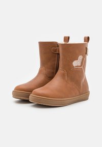 Botas tobilleras de imitación cuero marrón con cremallera lateral, puntera redondeada, superficie texturizada y un detalle en forma de corazón brillante en el lado exterior.