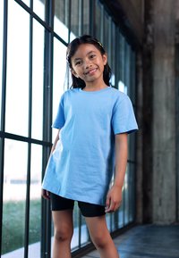 Heledsinine puuvillane T-särk lühikeste varrukatega, ümmargune kaelus, avar lõige, koos mustade lühikestega. Sujuv tekstuur, ei ole nähtavaid mustreid.