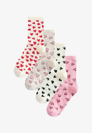 Fire par bomuldssokker i forskellige farver: hvide med røde hjerter, beige med pink hjerter, cremefarvede med sorte hjerter og lyserøde med lysere hjerter.