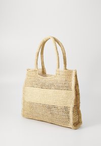 Geweven stro tas in lichtbeige met twee dikke handvatten, met een open geweven ontwerp en stevige secties voor een textuurlook.