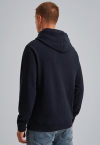 Sudadera azul marino con una textura suave, que presenta una costura central en la parte trasera y una capucha con cordón. Los puños y el dobladillo acanalados añaden un toque de detalle.