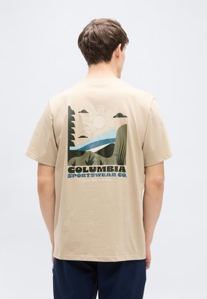 Beige cotton t-shirt featuring a graphic design on the back with a sun, hills, and water in green and blue tones. Brand text included.