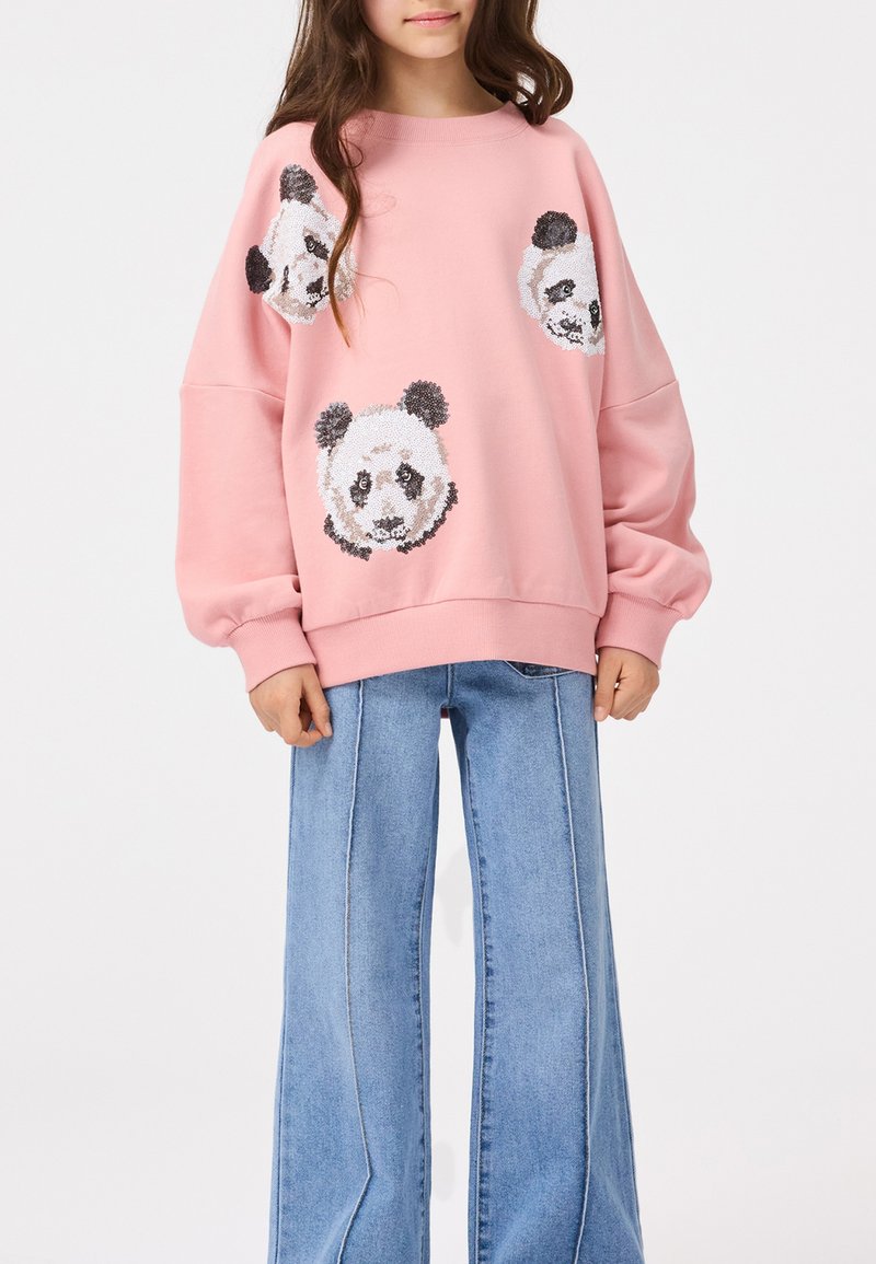 Pink sweatshirt made of cotton with loose fit, featuring four panda head appliqués in black and white. Paired with wide-leg denim jeans.