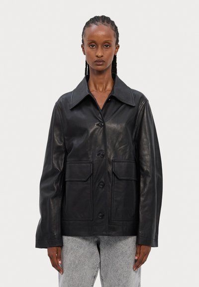 Must musta jope, millel on suur krae, esine nööp kinnis, ja kaks augulist taskut. Sile tekstuur ja mugav istuvus.