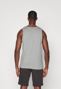 Grå tanktop med rund hals, lavet af bomuldsblanding, parret med mørke shorts, der viser et simpelt design og en komfortabel pasform.