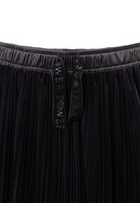 Gonna nera plissettata con vita elastica e due etichette in tessuto nero che recitano "POWER" e "FLOWER." Texture vellutata con finitura lucida.