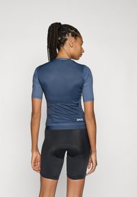 Maillot de cyclisme à manches courtes en bleu marine, fabriqué en tissu doux, au design ajusté, accompagné de shorts rembourrés noirs avec un insert circulaire.