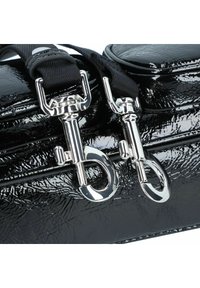 Zwarte lakleren tas met zilverkleurige accenten, voorzien van dubbele drukhaken en een gestructureerd oppervlak. Verstelbare zwarte schouderriem bevestigd.
