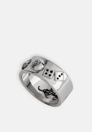 Bague en argent avec une surface lisse présentant des motifs en relief d'une boule de billard et de dés. Une texture remarquables et des formes audacieuses rehaussent l'intérêt visuel.
