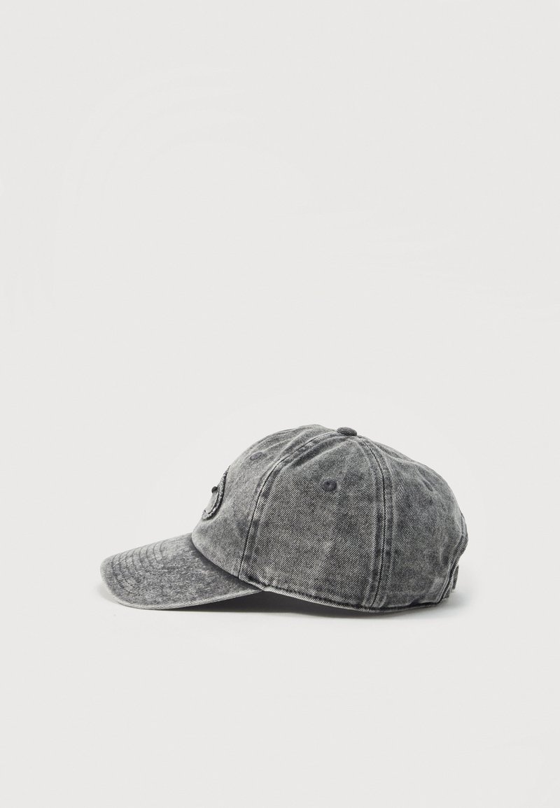 Casquette de baseball en denim gris usée avec une visière incurvée, vue de côté, isolée sur fond blanc uni.