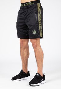 Pantaloni sportivi neri con dettagli verdi, tasca con zip e logo. Realizzati in tessuto liscio, presentano una comoda vita elastica.