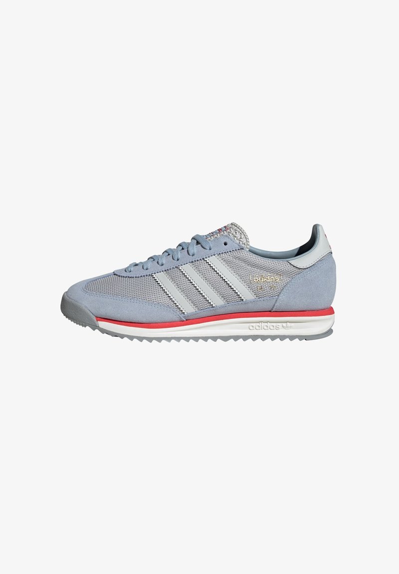 Light blue athletic shoes with gray suede and mesh upper, three white stripes, and red accents on the sole, featuring a textured tongue.