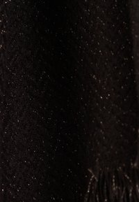 Bufanda negra con un patrón texturizado, que presenta hilos metálicos que crean un sutil brillo, rematada con detalles de flecos.