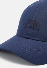 Tengerészkék sapka texturált anyagból, a "The North Face" dombornyomott logójával az elején, látható varrási részletekkel.