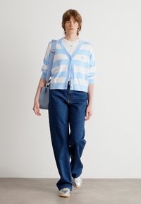 Light blue and white striped cardigan over a white top, paired with wide-leg blue jeans and silver sneakers. Accessory: light blue bag.