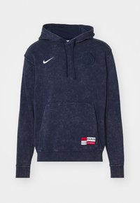 Granatowy hoodie wykonany z miękkiego materiału, z przednią kieszenią, logo Nike oraz emblematem Paris Saint-Germain. Teksturowana, luźna fit konstrukcja.
